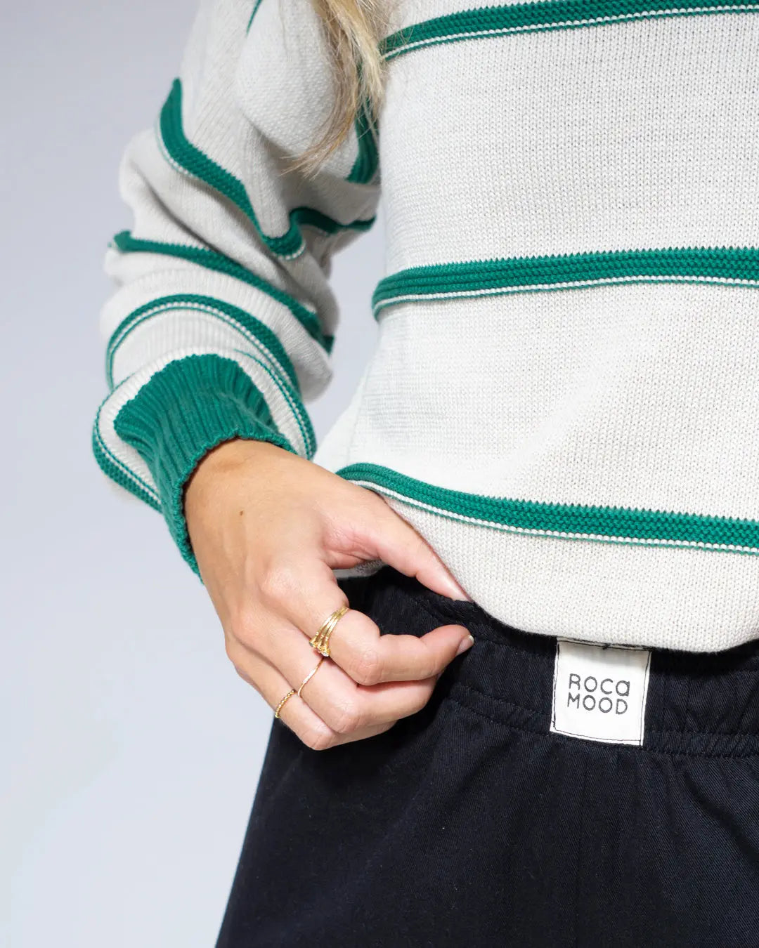 Suéter de punto gris con rayas verdes, estilo casual, combinado con pantalones negros de Roco Mood.