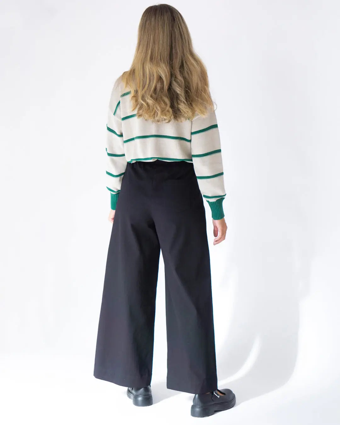 Suéter a rayas crema y verde con pantalones anchos negros, elegante y moderno para un look casual.