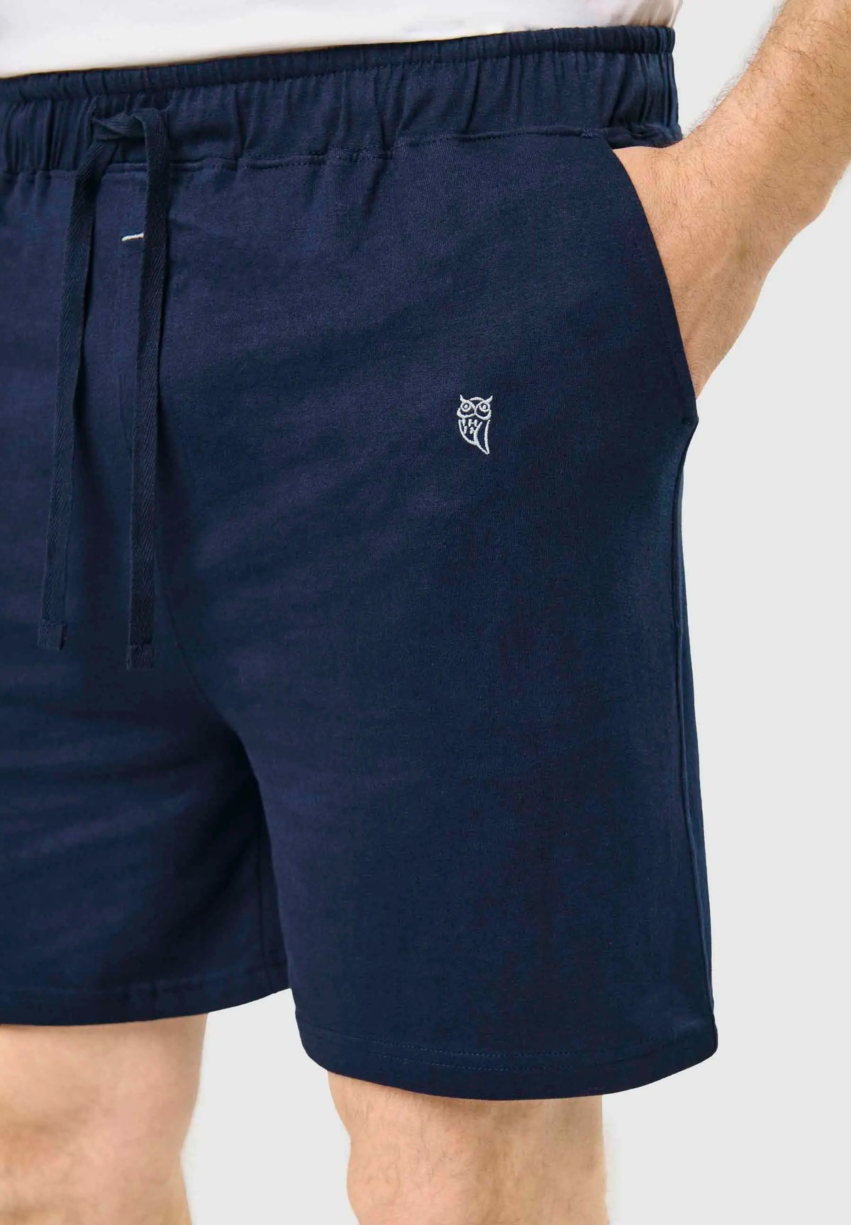 Pantalón corto de pijama para hombre en punto liso azul, con cintura elástica, cordón ajustable y pequeño logo bordado.