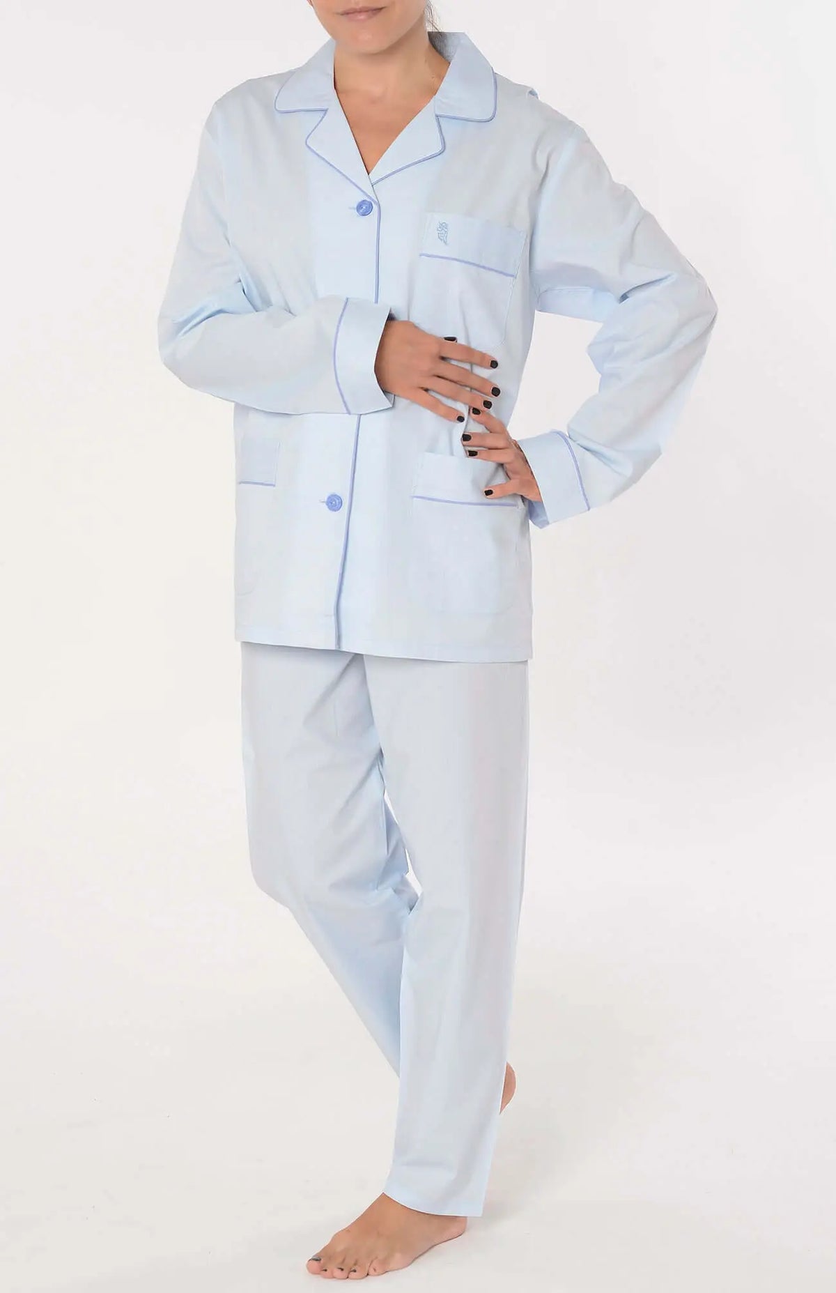 Pijama largo azul celeste para mujer con solapa, botones, bolsillos, ribetes y textura labrada sobre fondo blanco.