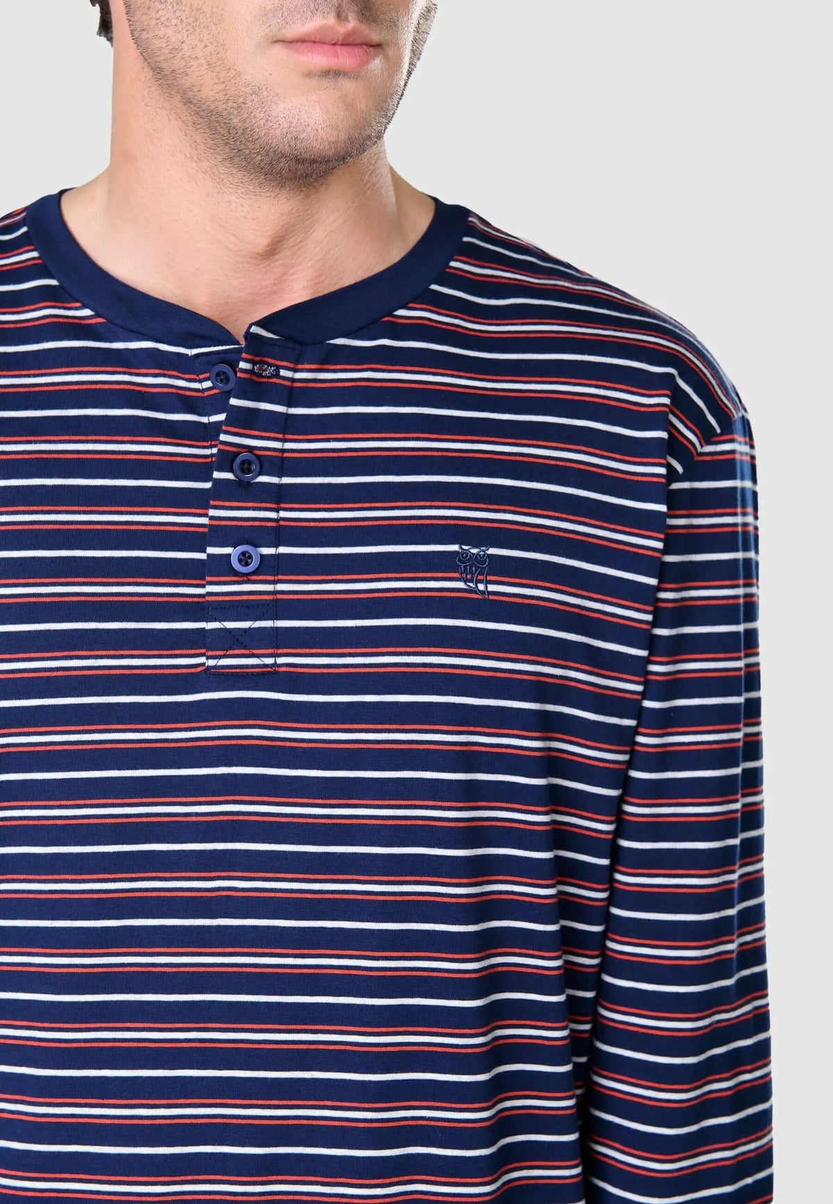 Camiseta de pijama azul a rayas blancas y rojas con tapeta de tres botones y logo bordado de El Búho Nocturno.