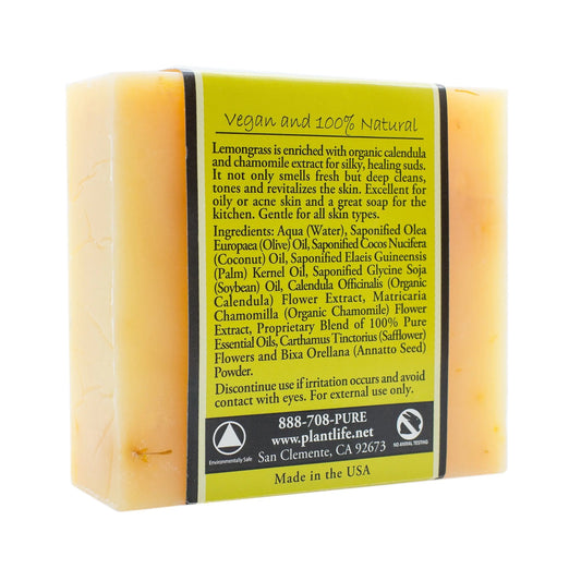 Rectangular bar of yellow lemongrass soap wrapped in a green and black label listing ingredients and benefits.