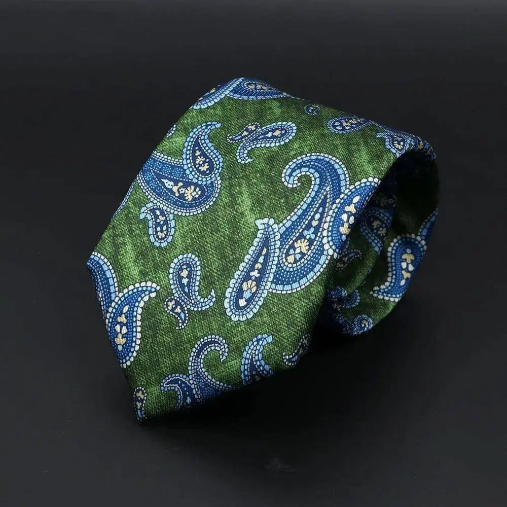 Corbata verde texturizada con estampado paisley en tonos azules y detalles claros, estilo elegante y clásico.