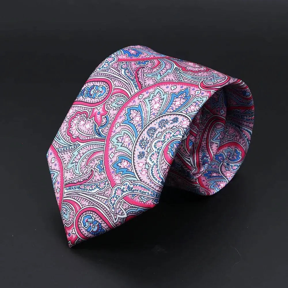 Corbata de seda con estampado paisley en tonos rosa, azul y blanco sobre fondo oscuro, estilo clásico y elegante.