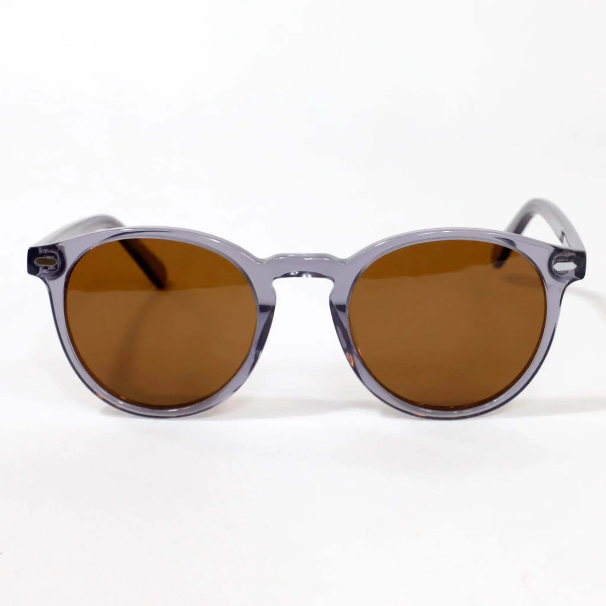Gafas de sol redondas con montura de acetato gris cristal transparente y cristales tintados de color marrón.