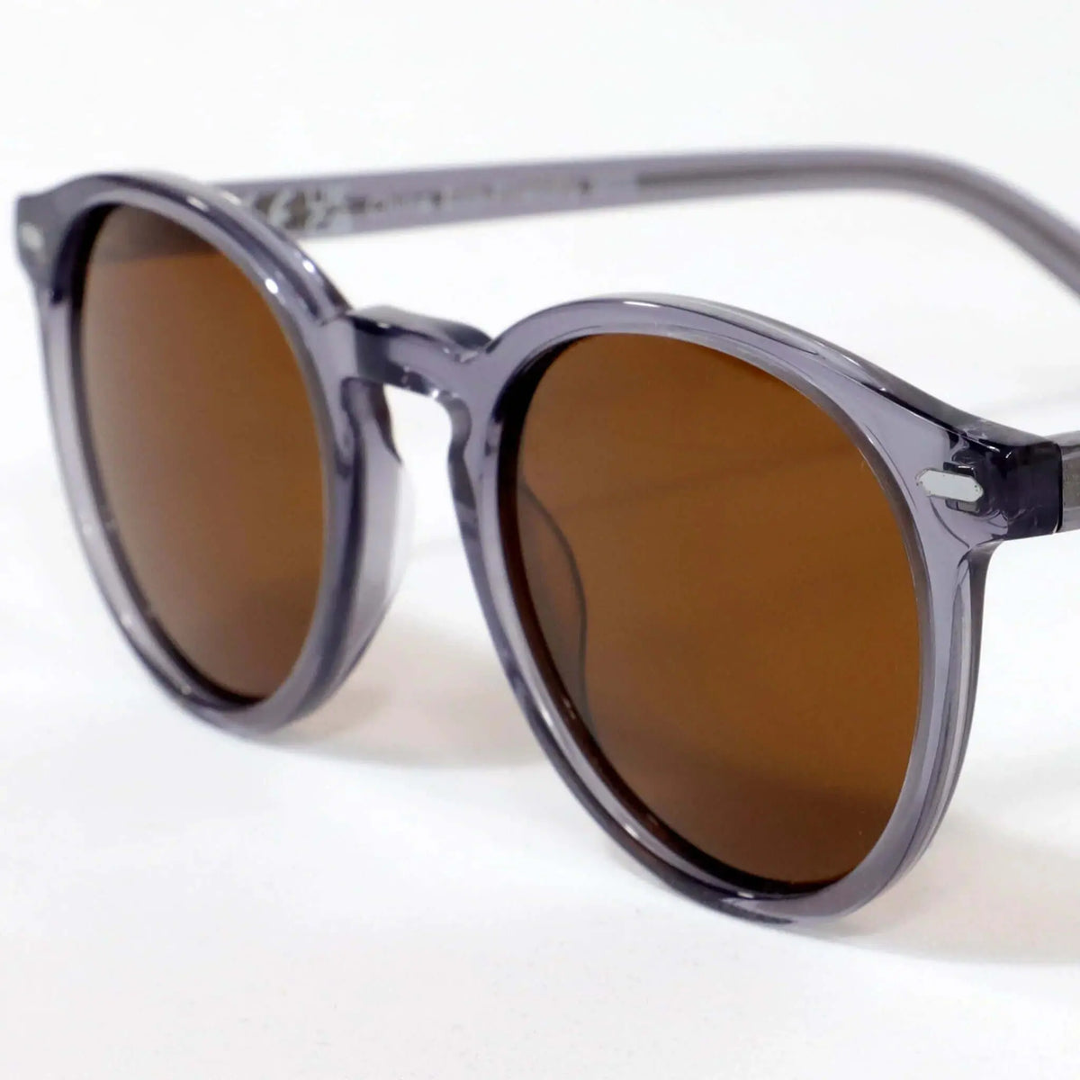 Gafas de sol redondas con montura de acetato gris translúcido y lentes oscuras de estilo clásico y casual.