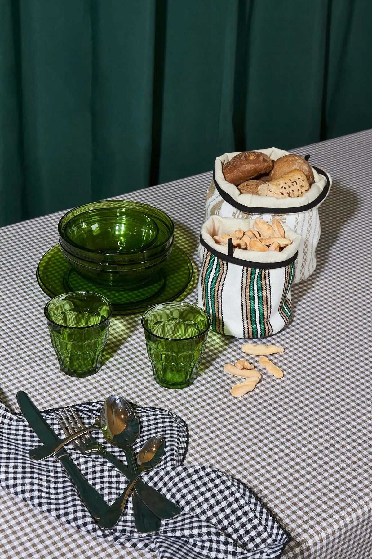 Cestos de tela con rayas verdes y beige, tejido tradicional, forma cilíndrica y borde superior negro sobre mesa puesta.