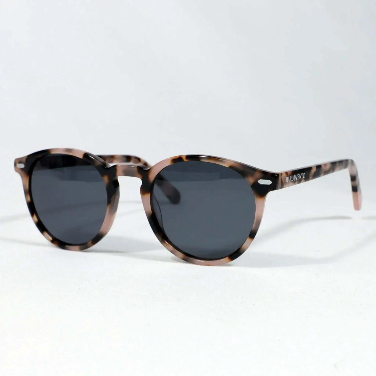 Gafas de sol redondas con montura de acrílico estampado carey en tonos marrones y cristales oscuros sobre fondo blanco.