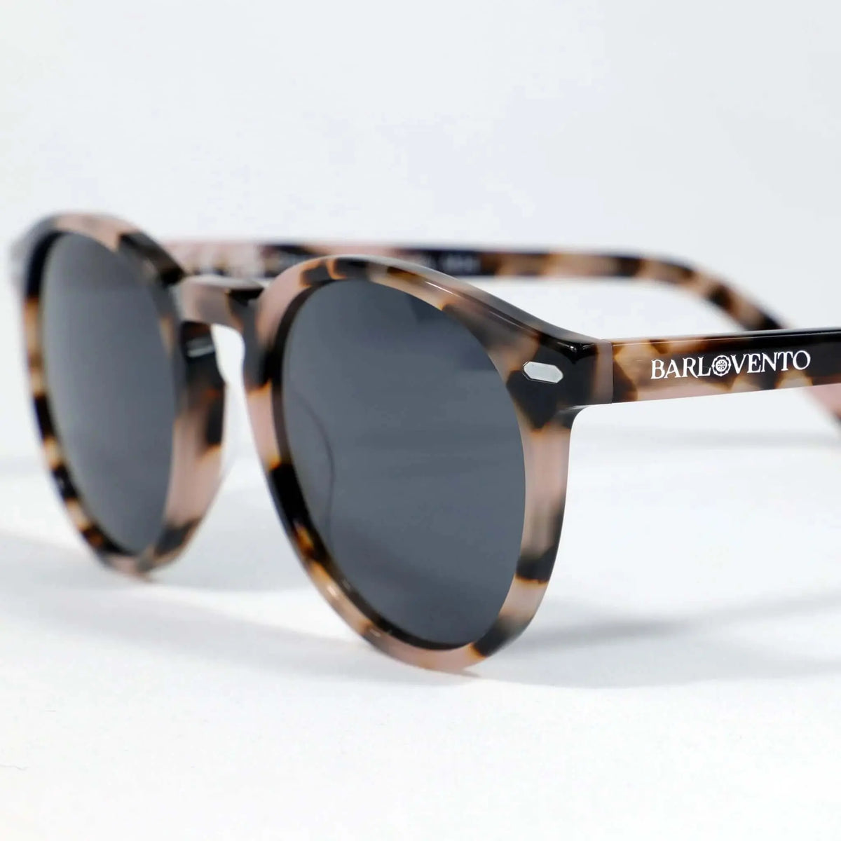 Gafas de sol redondas con montura de acrílico estampado carey en tonos marrones y cristales oscuros sobre fondo blanco.