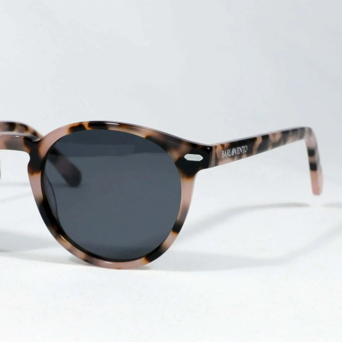 Gafas de sol redondas con montura de acrílico estampado carey en tonos marrones y cristales oscuros sobre fondo blanco.
