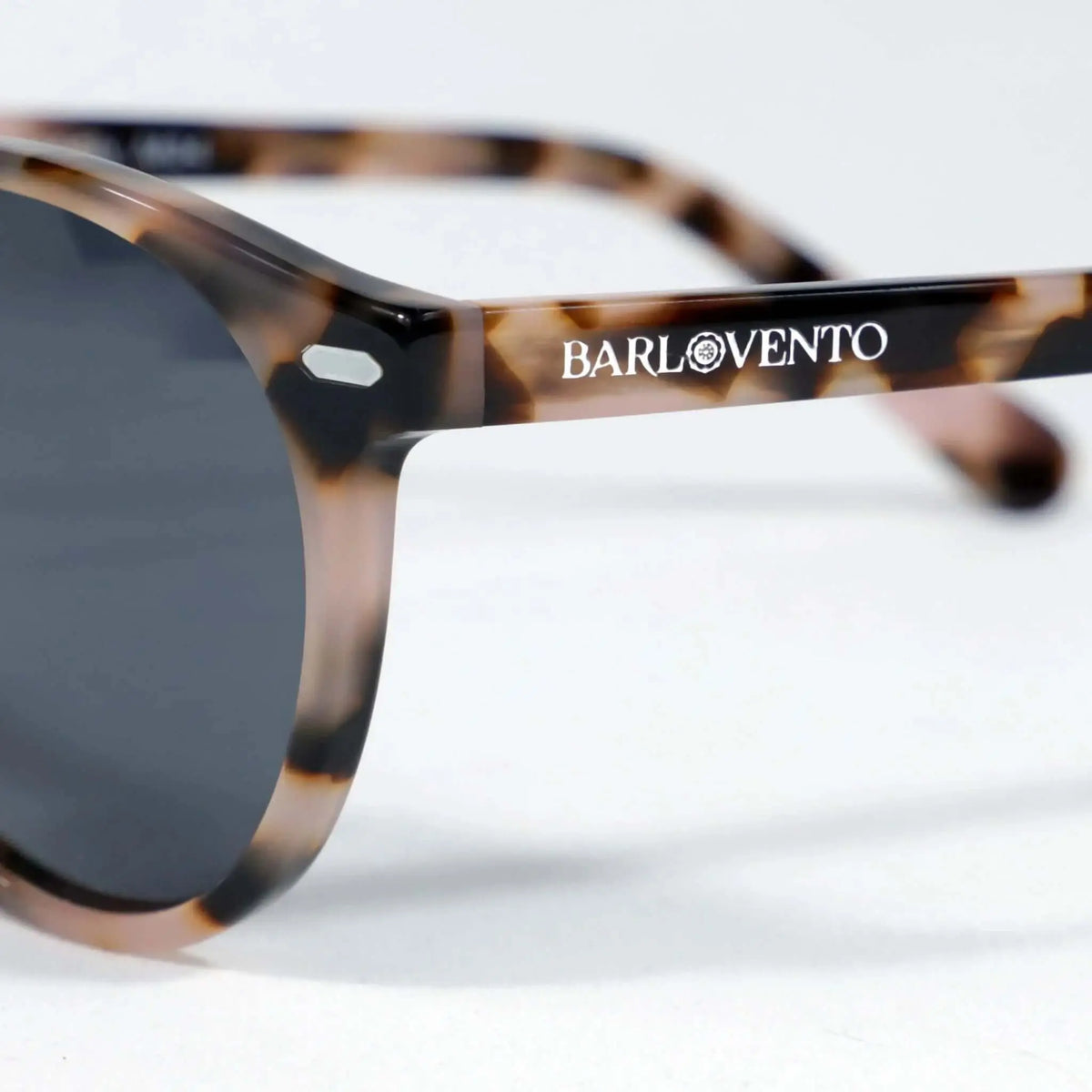 Gafas de sol redondas con montura de acrílico estampado carey en tonos marrones y cristales oscuros sobre fondo blanco.
