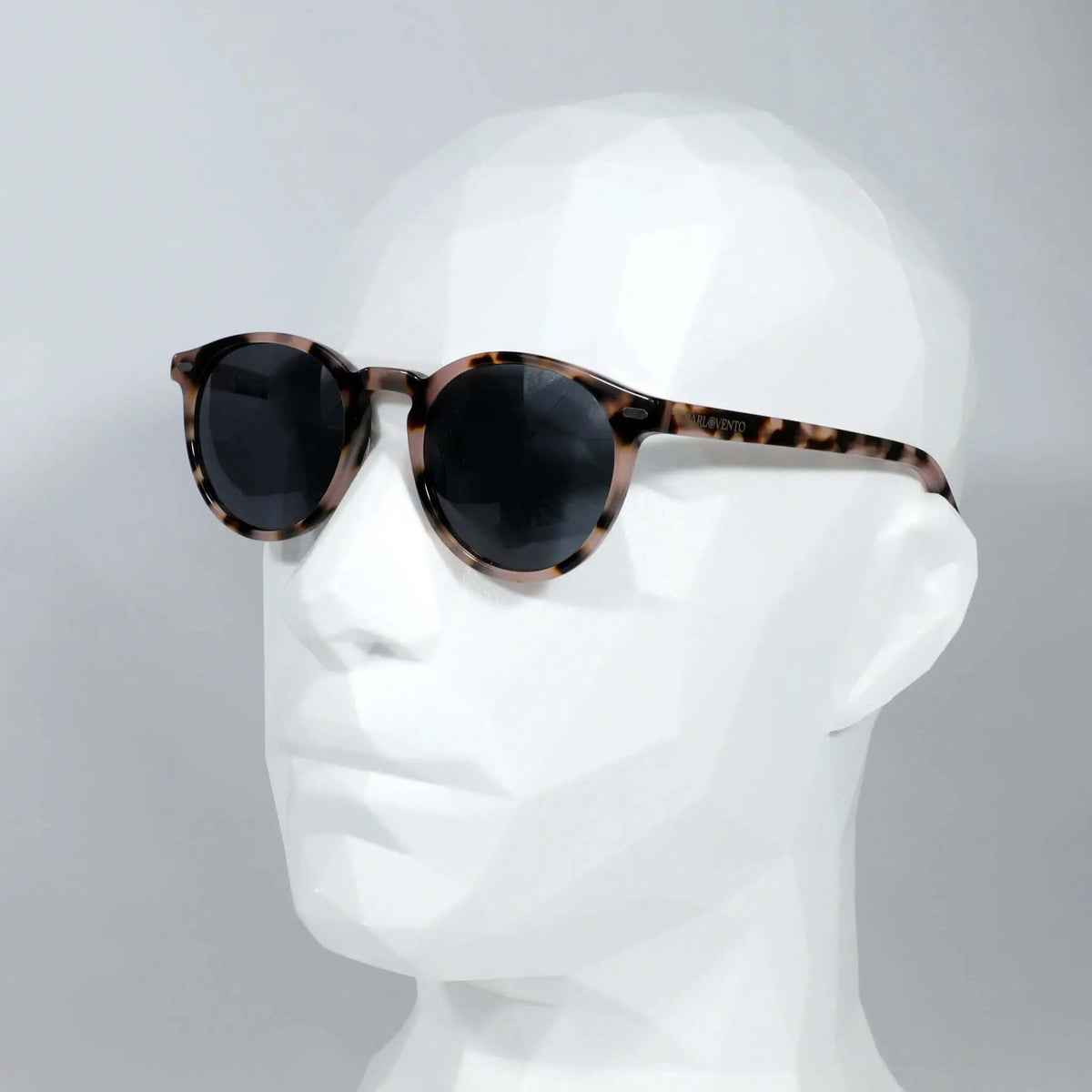 Gafas de sol redondas con montura de acrílico estampado carey y cristales oscuros sobre maniquí blanco.