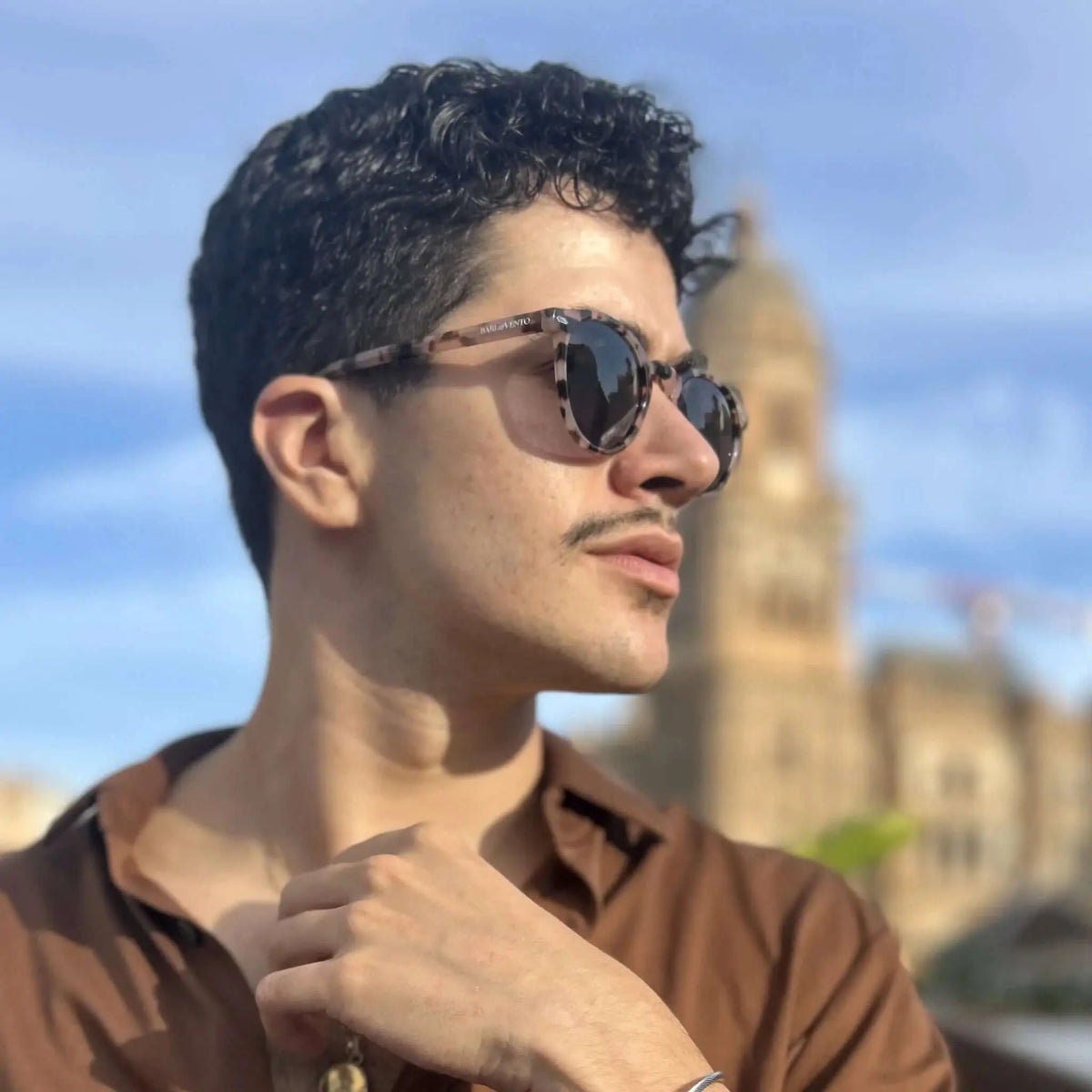 Hombre con gafas de sol redondas de carey acrílico, montura estampada y cristales oscuros, estilo vintage y elegante.