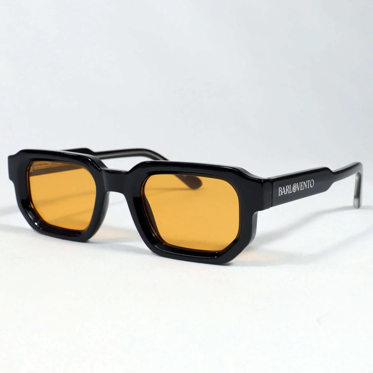 Gafas de sol rectangulares de montura negra brillante y cristales naranjas con diseño robusto y estilo moderno.