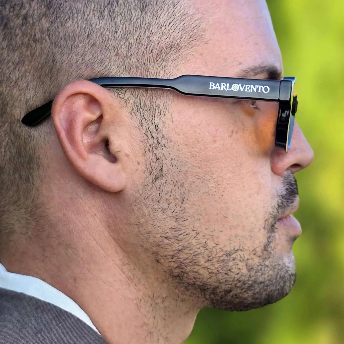 Perfil de hombre con gafas de sol negras de montura gruesa y lentes naranjas en estilo moderno y llamativo.