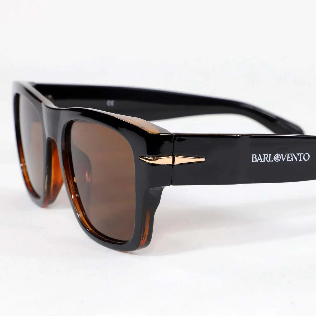 Gafas de sol retro negras con montura de acetato brillante, lentes marrones y detalles dorados en las varillas.