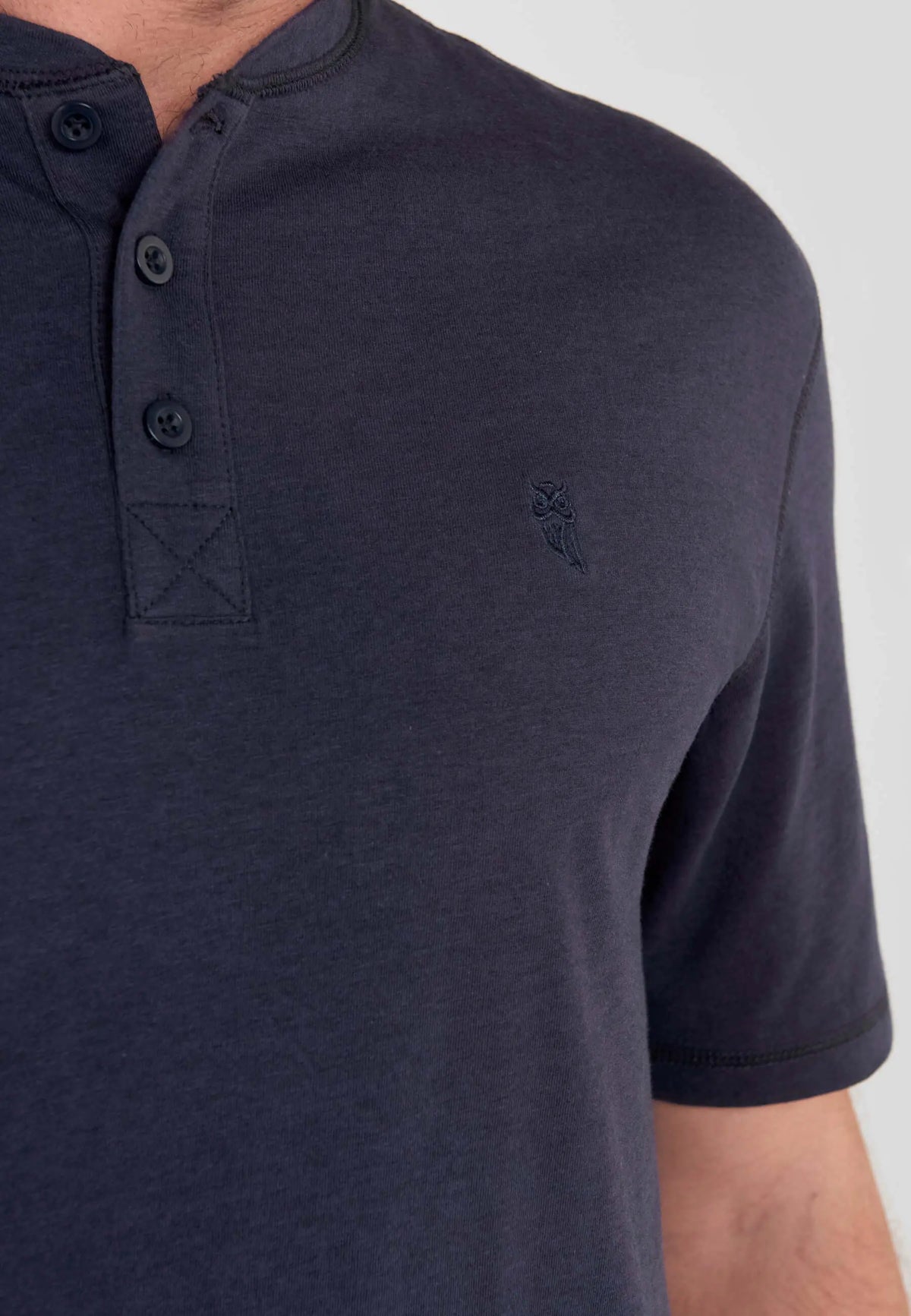 Camiseta de pijama azul marino, cuello mao con tres botones y logo de búho bordado en tejido de punto liso.