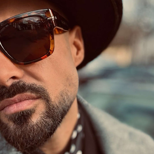 Gafas de sol retro con montura de carey y diseño cuadrado, lucidas por un hombre con sombrero y estilo elegante.