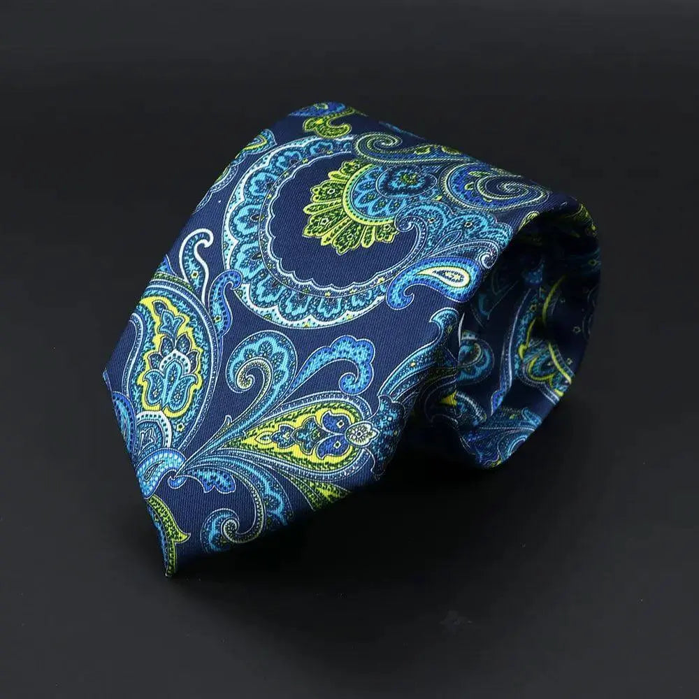 Corbata azul marino con elegante estampado paisley en tonos turquesa, amarillo y azul claro sobre fondo oscuro.