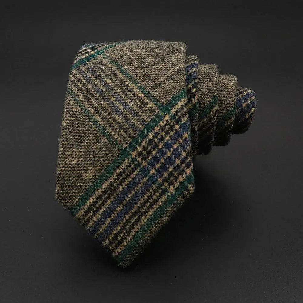 Corbata de lana enrollada con estampado de cuadros en tonos marrón, verde y azul sobre fondo oscuro. Estilo invernal.