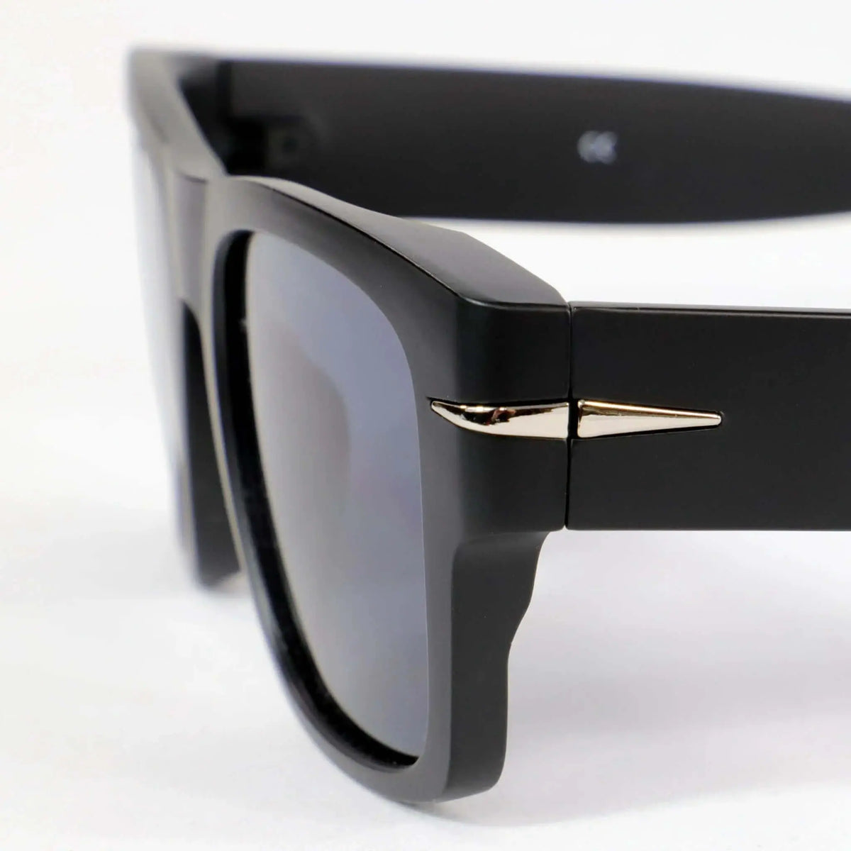 Gafas de sol negras cuadradas con montura mate, cristales oscuros y detalle metálico plateado en la bisagra.