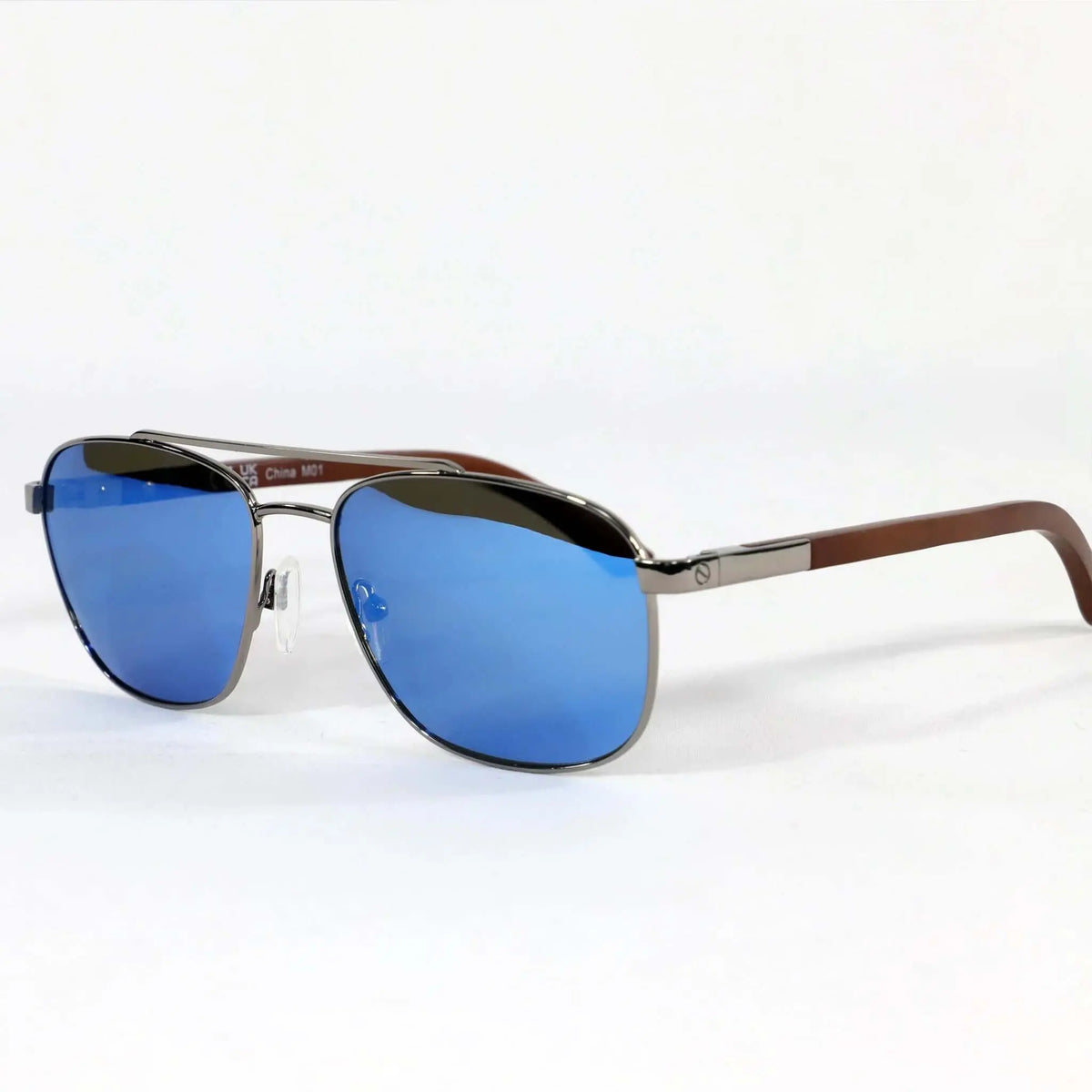 Gafas de sol tipo aviador con montura metálica, lentes azules espejadas y patillas de madera sobre fondo blanco.