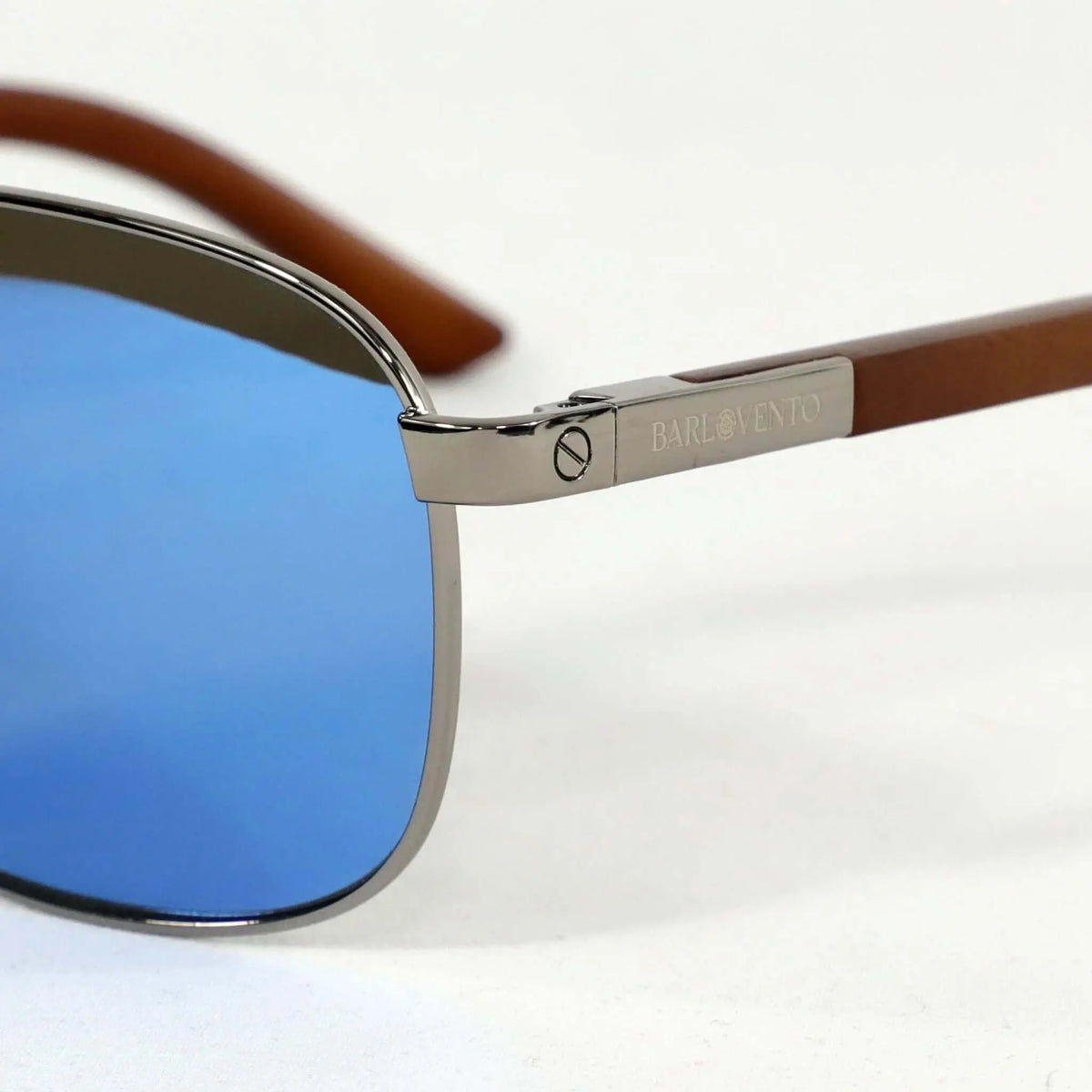 Gafas de sol con lentes azules, montura metálica plateada y patillas de madera natural con detalles grabados.
