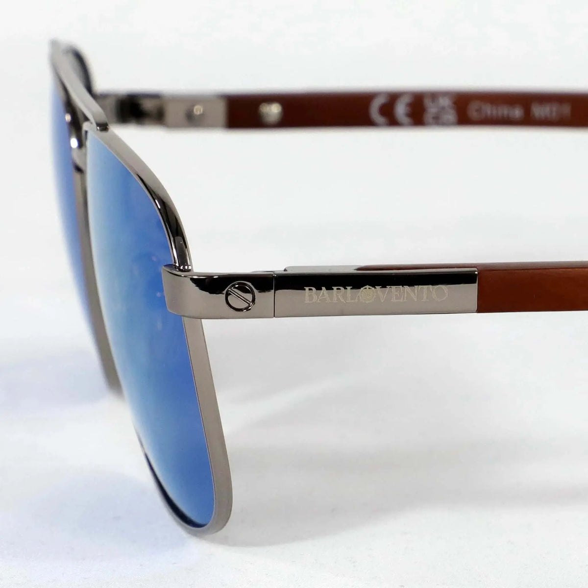 Gafas de sol estilo aviador con lentes azules reflectantes, montura metálica y patillas de madera veteada.