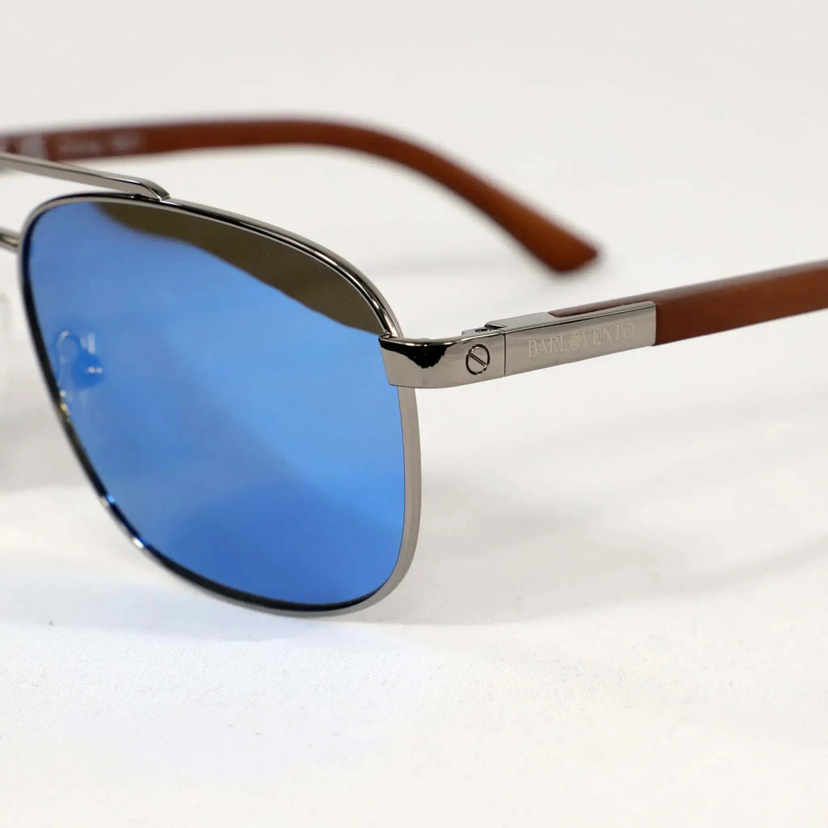 Gafas de sol estilo aviador con lentes azules reflectantes, montura metálica y patillas de madera marrón.