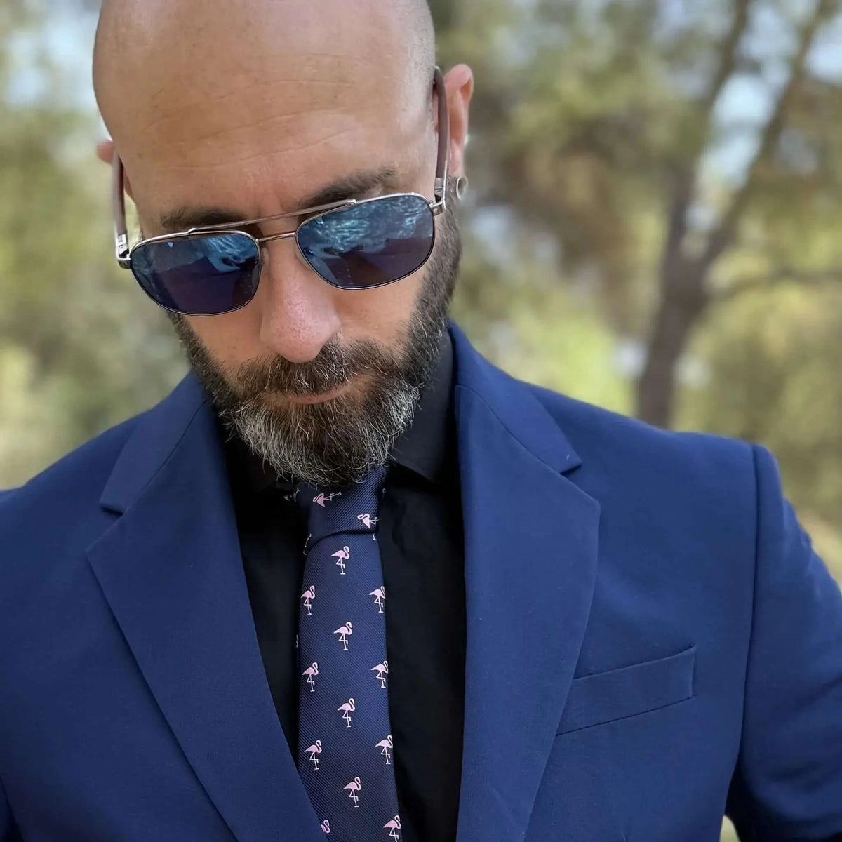 Hombre con traje azul y gafas de sol aviador con lentes azules y patillas de madera grabadas al aire libre.