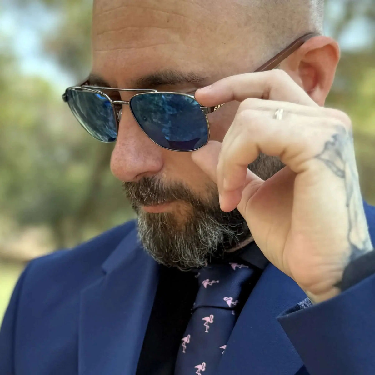 Hombre con traje y corbata usando gafas estilo aviador con lentes azules y patillas de madera grabadas.