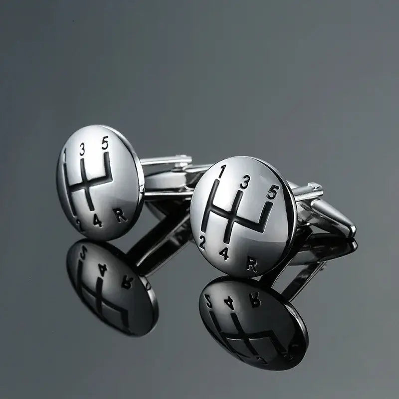 Gemelos para amantes de los coches con diseño de palanca de cambios plateada y detalles en negro.