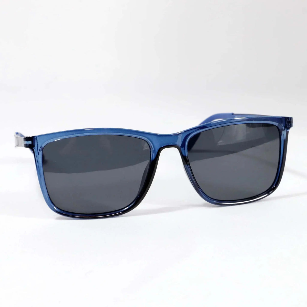 Gafas de sol unisex con montura rectangular de acetato azul translúcido y cristales oscuros sobre fondo blanco.