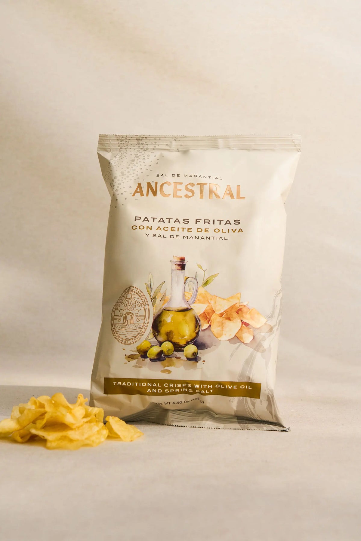 Bag of potato chips featuring an illustration of olive oil and crisps, with loose chips in the foreground.