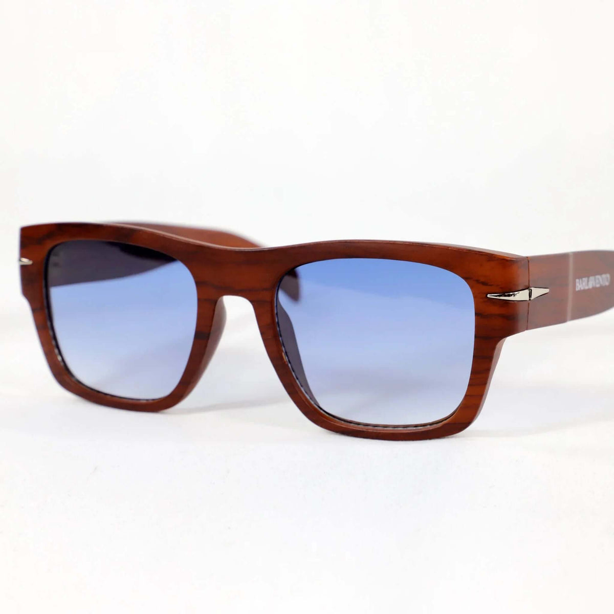 Gafas de sol cuadradas con montura estilo madera marrón y lentes azules degradadas sobre fondo blanco.