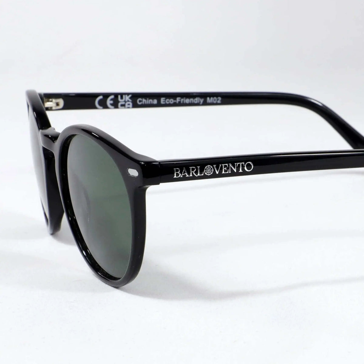Gafas de sol unisex con montura negra brillante de estilo redondeado y lentes polarizadas en color verde oscuro.