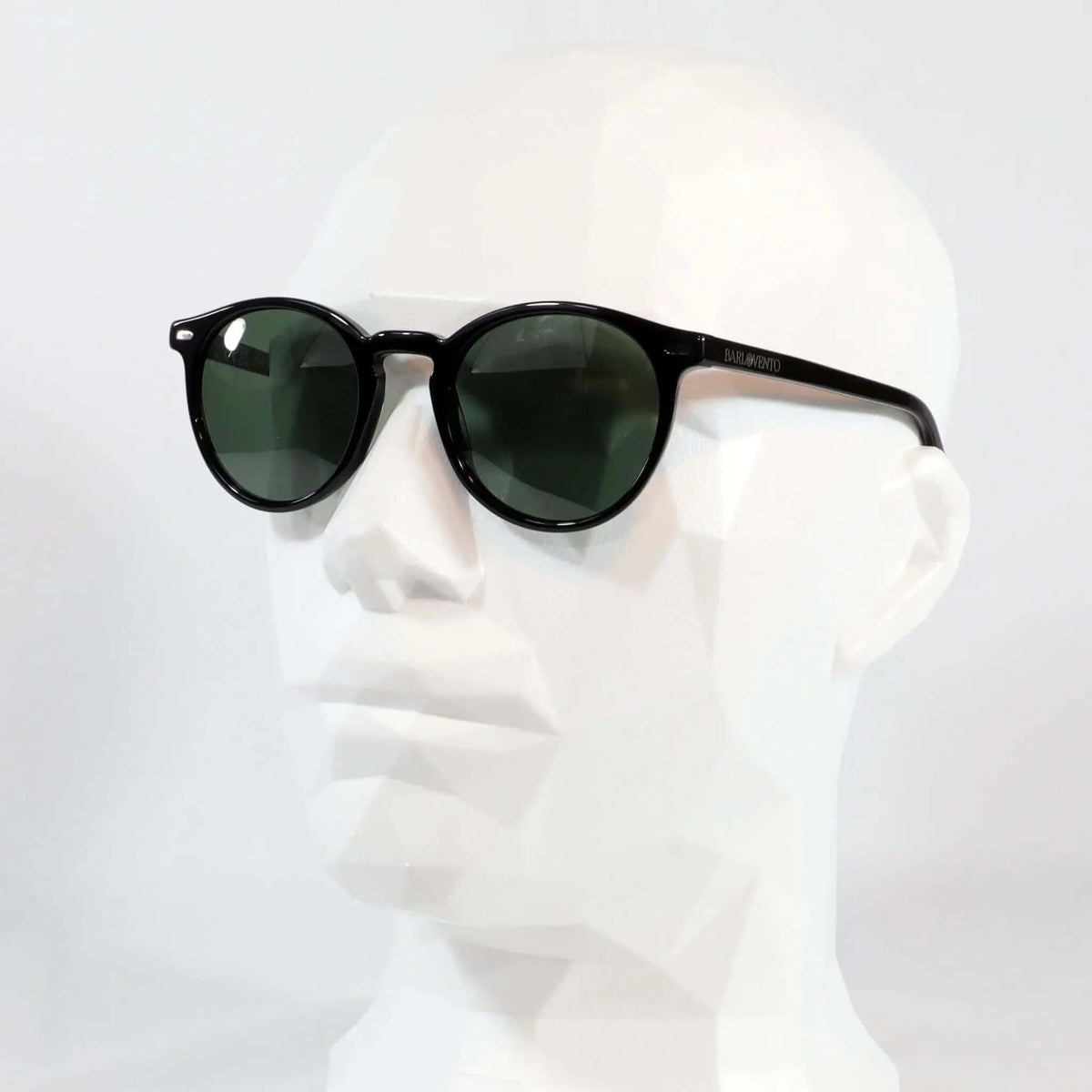 Gafas de sol unisex con montura redonda negra brillante y lentes polarizadas de color verde oscuro sobre maniquí.
