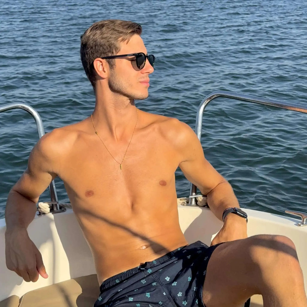 Hombre con gafas de sol negras de montura clásica y cristales verdes polarizados en un barco.