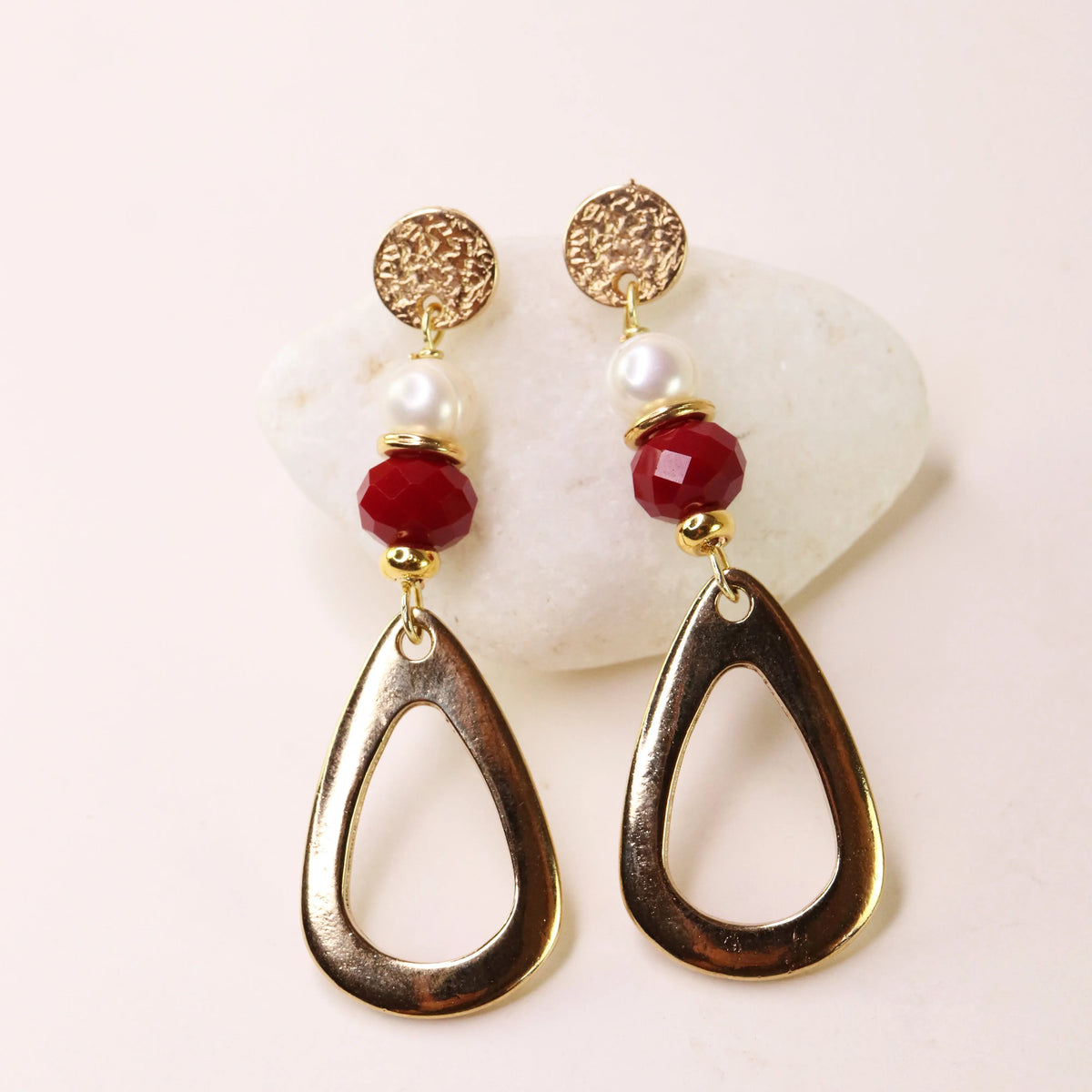 Pendientes dorados con perlas y cuentas rojas, diseño moderno y elegante, ideal para ocasiones especiales.