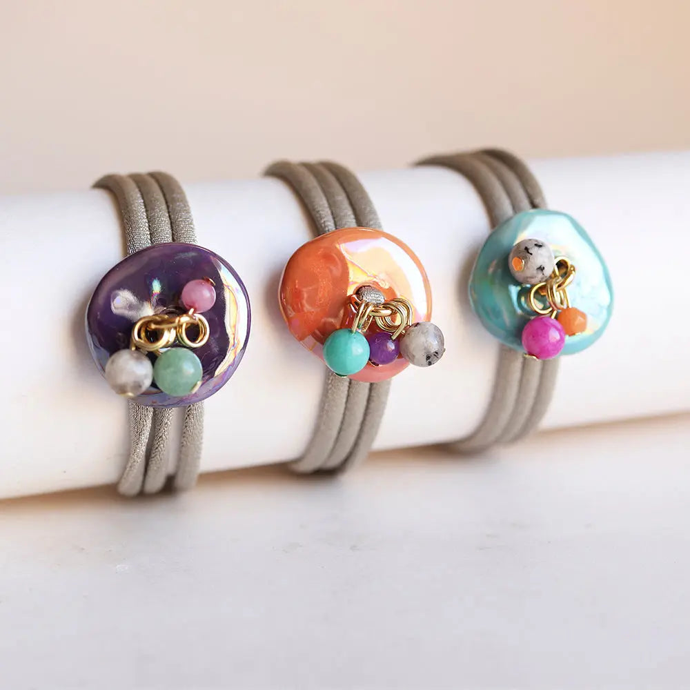 Pulseras de goma con charm colorido en púrpura, naranja y turquesa, estilo moderno y vibrante.