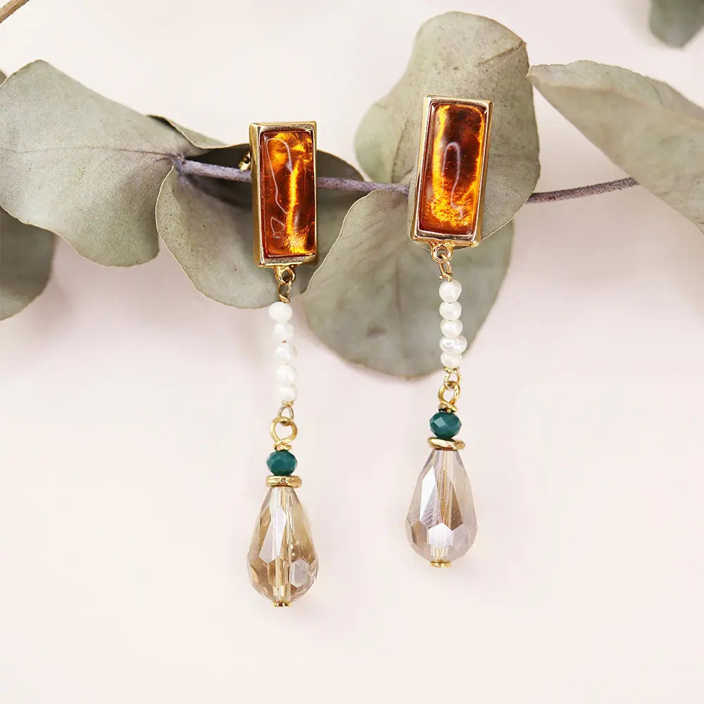 Pendientes elegantes con ámbar y perlas, acabados en dorado, con detalles en verde y cristal, estilo bohemio.