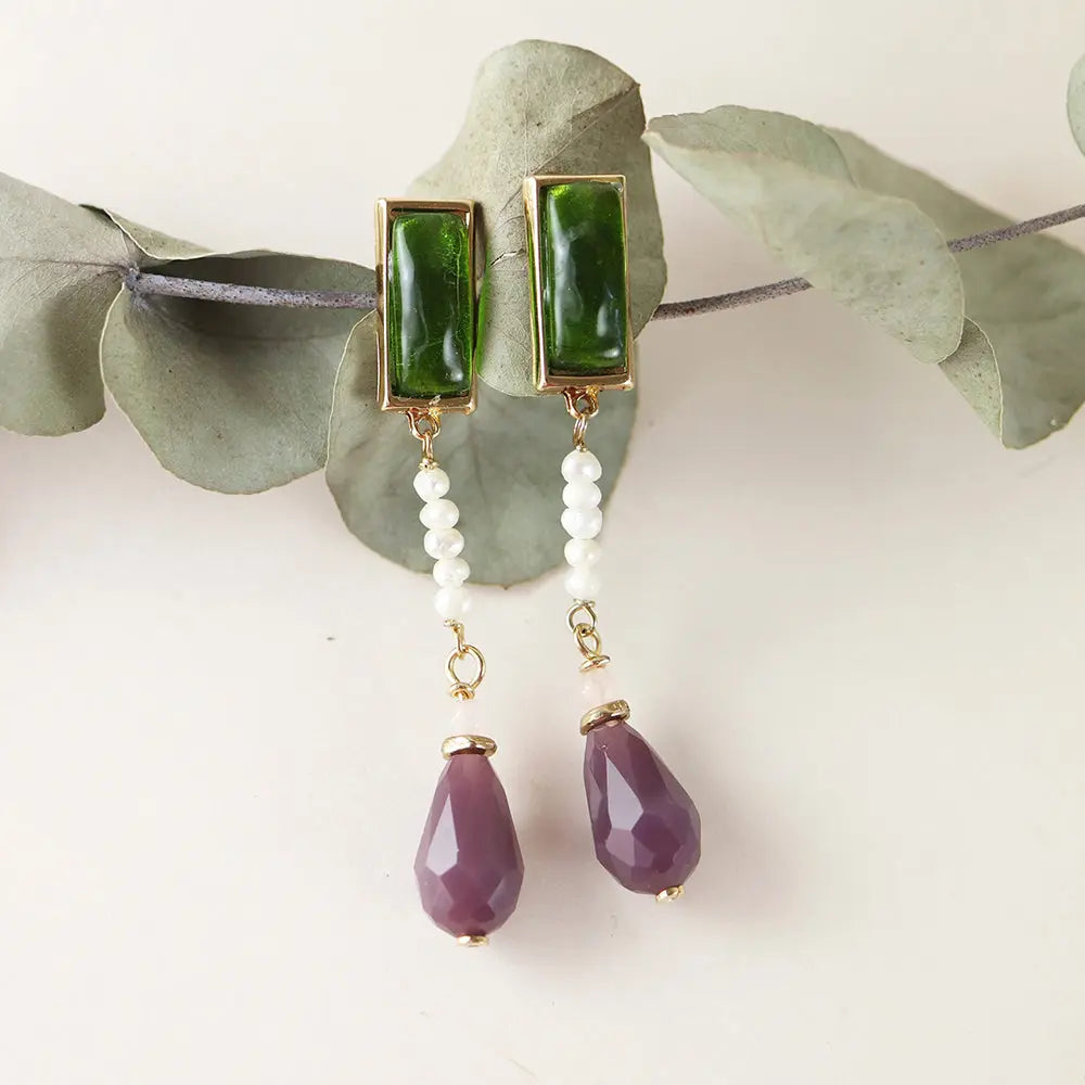 Pendientes de botón verdes con perlas blancas y gotas moradas, estilo elegante y sofisticado.