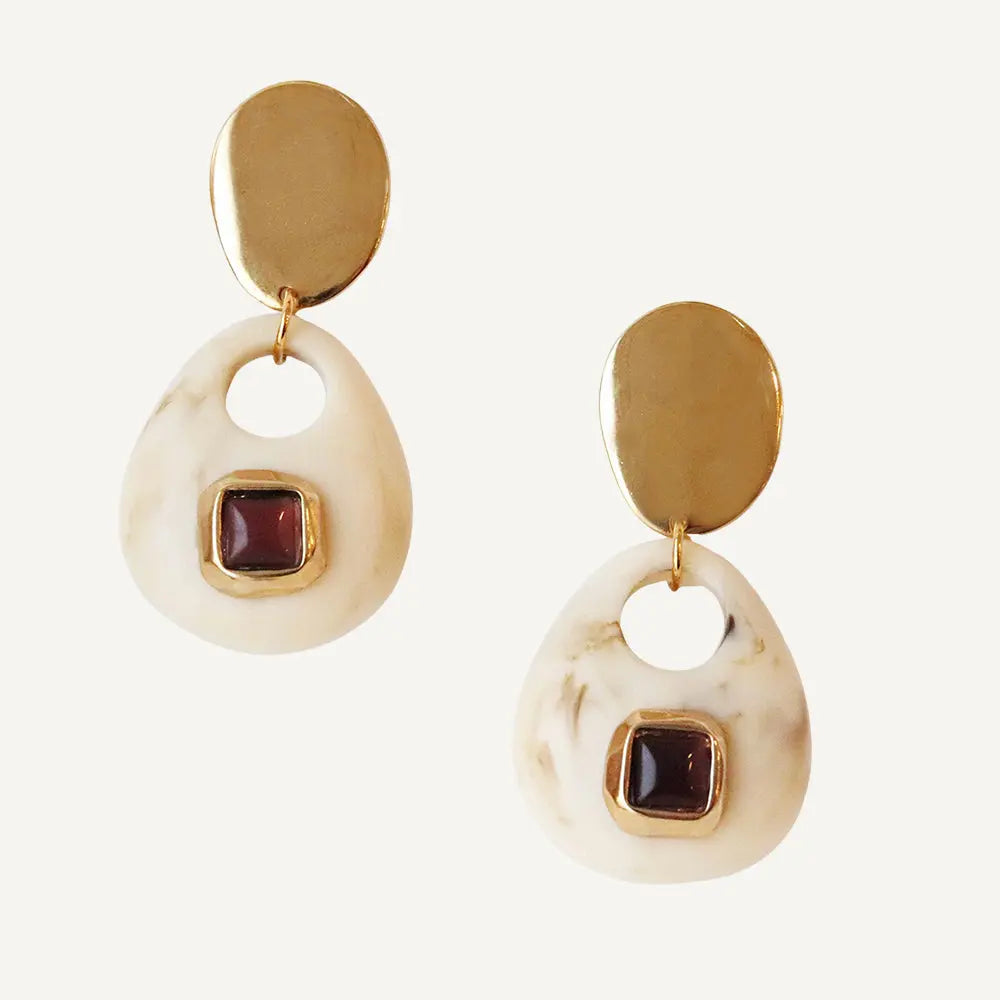 Pendientes de resina blanca con detalles en dorado y piedra granate, estilo moderno y elegante.