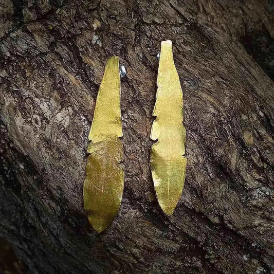 Pendientes largos de metal dorado en forma de pluma, elegantes y modernos, ideales para cualquier ocasión.