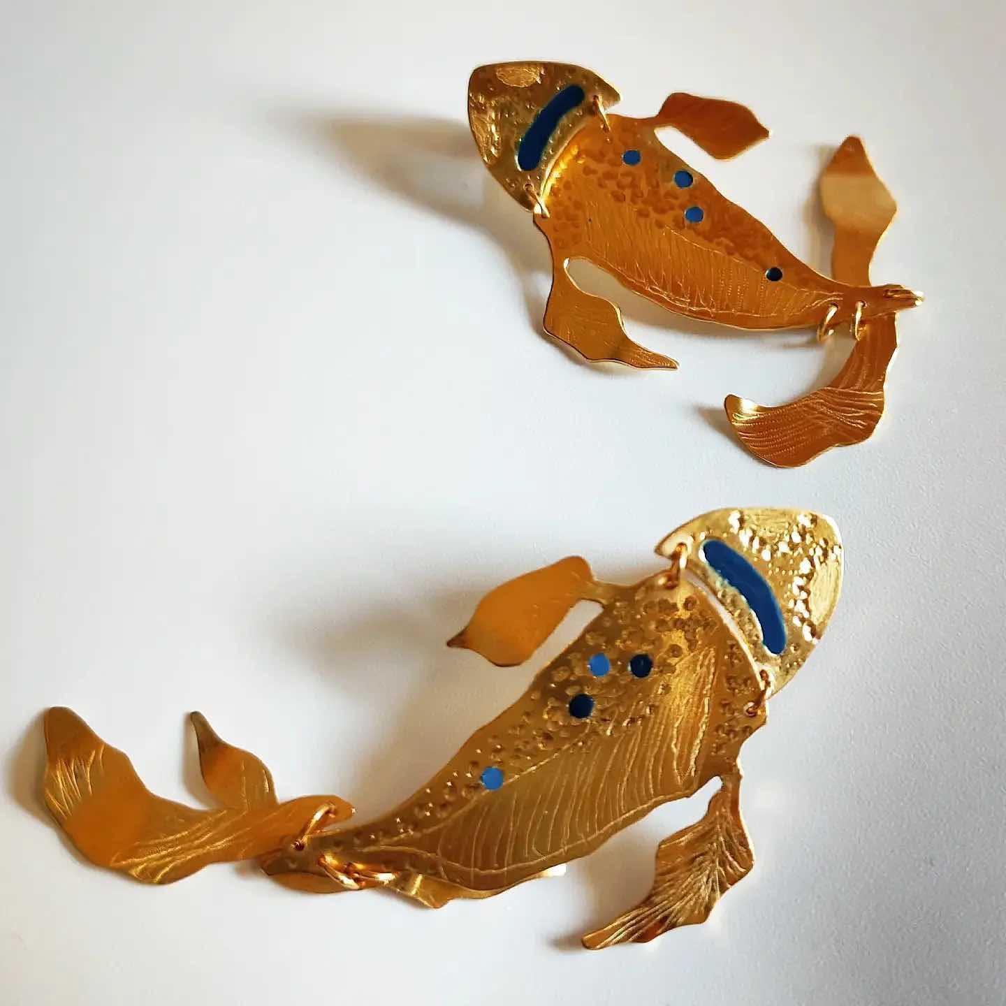 Pendientes de pez koi dorados, detalle en azul y negro, diseño elegante y artístico en metal.