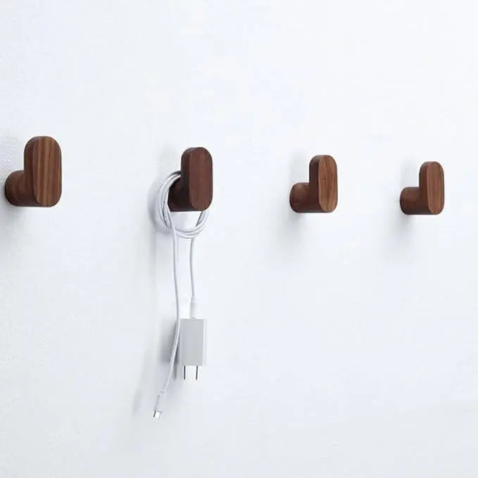 Cuatro perchas de pared en madera oscura con diseño minimalista, montadas sobre una pared blanca lisa.