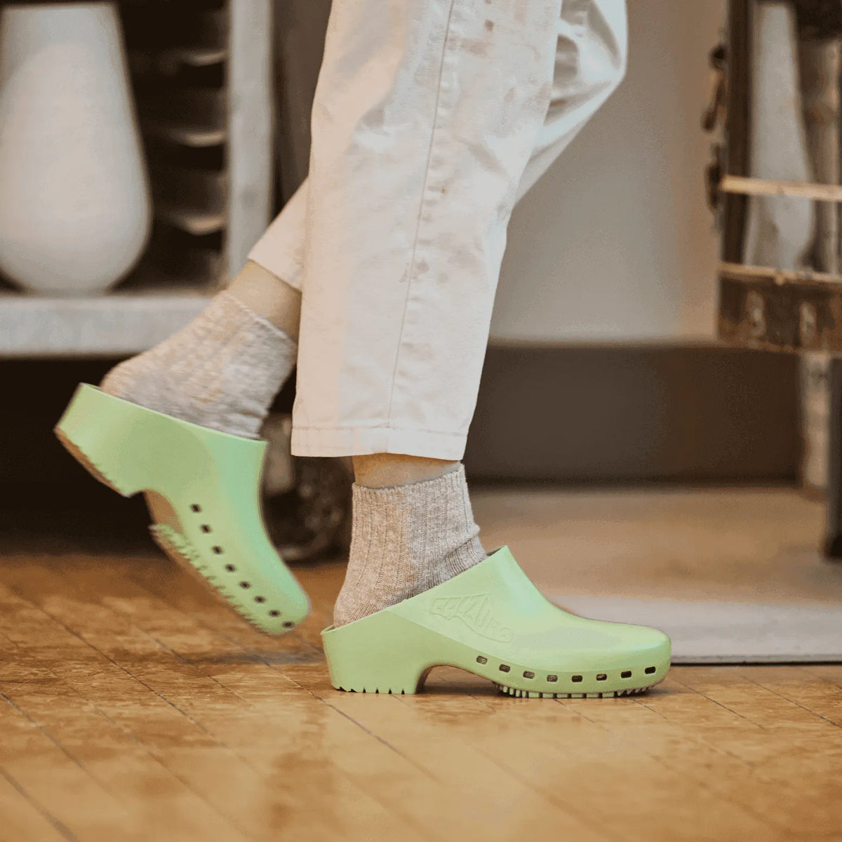 Light green eco-friendly clogs paired with gray socks, perfect for casual and comfortable outdoor wear.