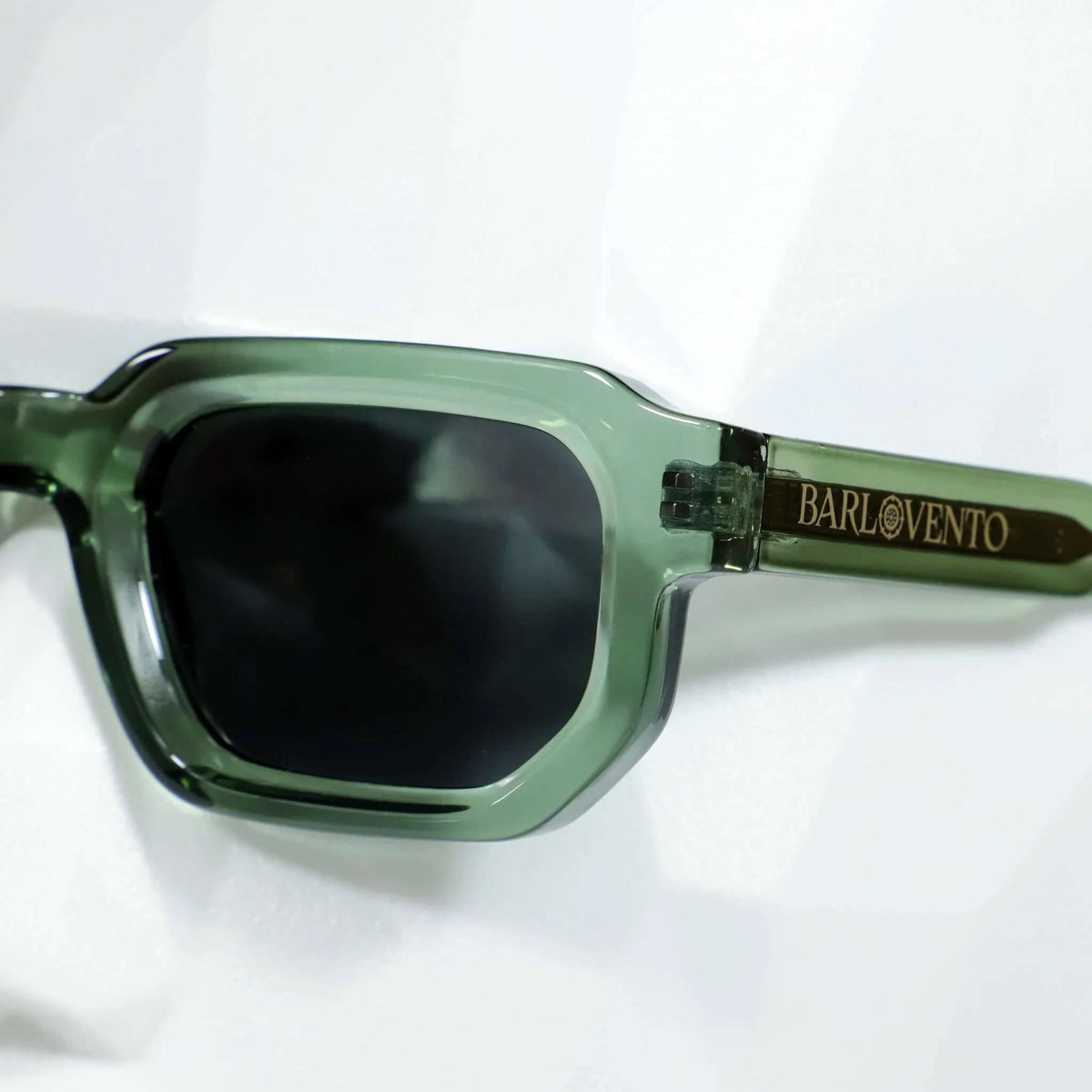 Gafas de sol rectangulares con montura de acetato verde translúcido y lentes oscuras. Estilo moderno y definido.