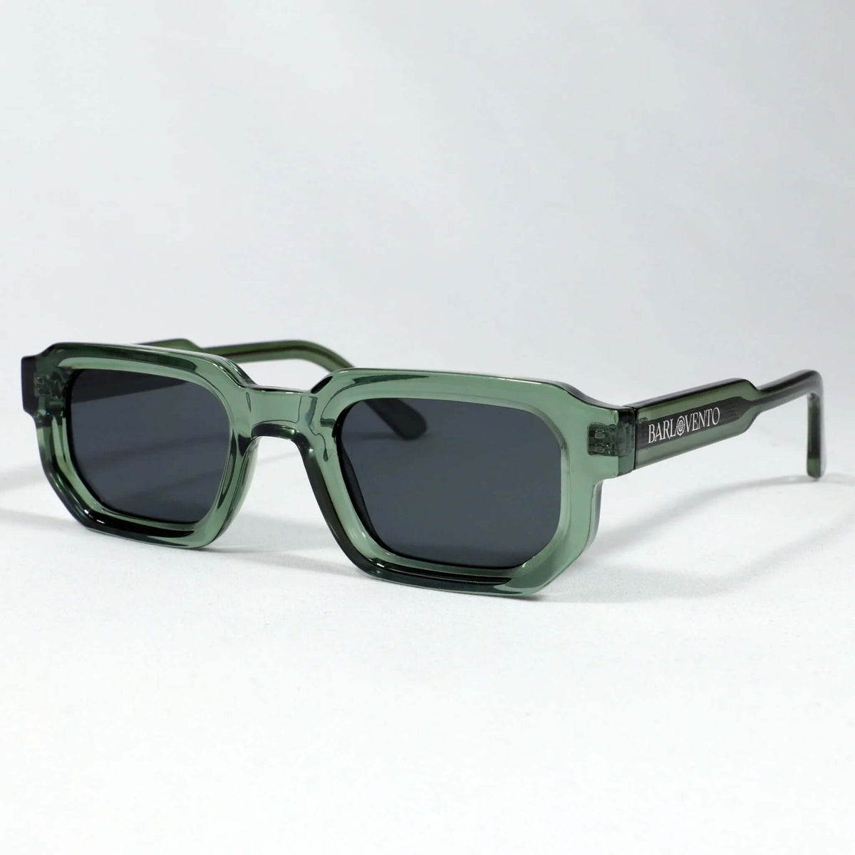Gafas de sol de montura rectangular en acetato verde translúcido con lentes oscuras estilo moderno.