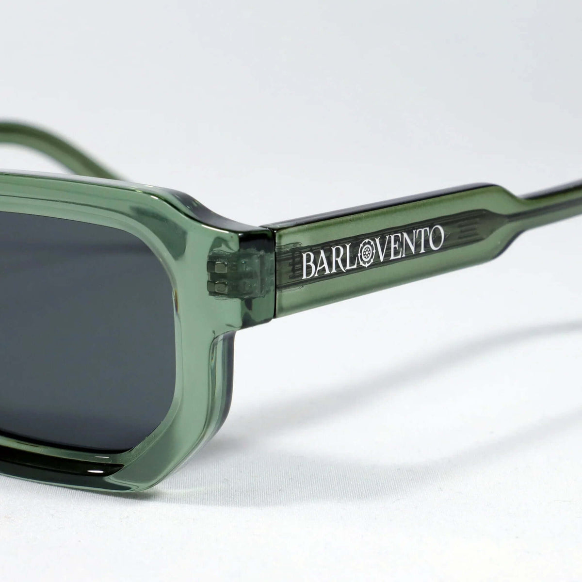 Gafas de sol de montura rectangular en acetato verde translúcido con lentes oscuras. Diseño moderno y minimalista.